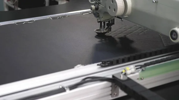 Roboternähmaschine. Der Computer steuert die Nähmaschine. Nähautomaten. automatisierte maschinelle Stickmuster auf Kunstleder. Robotik arbeitet in der Schneiderei-Fertigungslinie. — Stockfoto