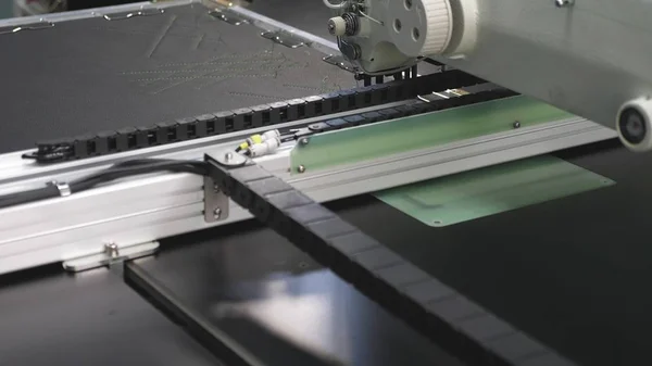 로봇 재봉틀. 컴퓨터는 재봉틀을 제어합니다. 자동 재봉틀. 인공 가죽에 자동 기계 자수 패턴. 로봇 공학은 테일러링 생산 라인에서 작동. — 스톡 사진
