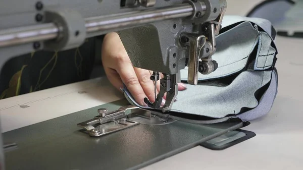 process of sewing leather goods. The needle of the sewing machine in motion. two needles of the sewing machine quickly moves up and down, close-up. Tailor sews black leather in a sewing workshop.