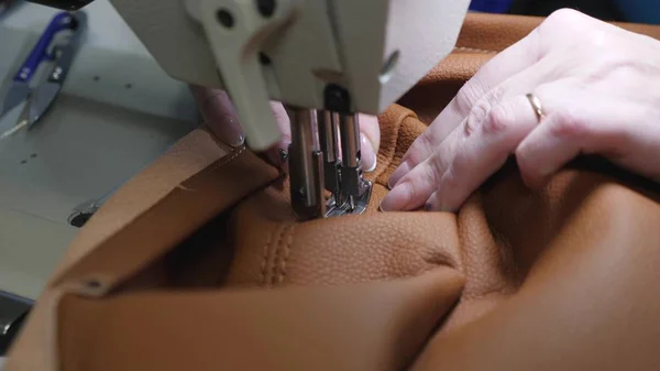 Nähprozess von Kunstleder. Nadel der Nähmaschine in Bewegung. Zwei Nadeln der Nähmaschine bewegen sich schnell auf und ab, aus nächster Nähe. Schneiderin näht braunes Leder in Nähwerkstatt. — Stockfoto