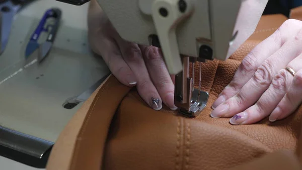process of sewing artificial leather. needle of sewing machine in motion. two needles of sewing machine quickly moves up and down, close-up. tailor sews brown leather in a sewing workshop.