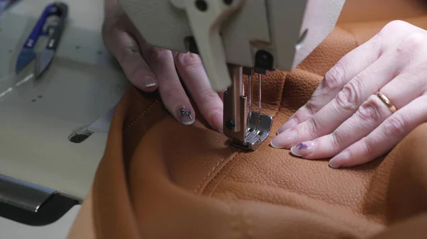 Processus de couture de cuir artificiel. aiguille de machine à coudre en mouvement. deux aiguilles de machine à coudre se déplace rapidement de haut en bas, gros plan. tailleur coud cuir marron dans un atelier de couture . — Photo