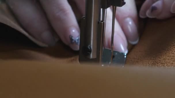 ミシンの2本の針はすぐに上下に動きます。動いているミシンの針、クローズアップ。革製品を縫うプロセス。テーラーは縫製ワークショップで黒い革を縫う. — ストック動画