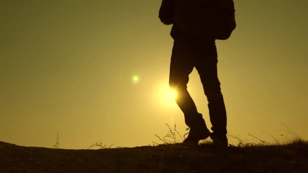 Pernas de viajantes vão no topo da montanha em raios de um belo sol. trabalho de equipa de pessoas de negócios. três viajantes descem da colina em raios de sol um após o outro vão além do horizonte. Movimento lento . — Vídeo de Stock