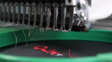 Robotics, üretim hattını uyarlamada çalışmaktadır. Robot dikiş makinesi. otomatik dikiş makinesi. siyah bez üzerinde kırmızı iplikler ile otomatik bir makine nakış desen.