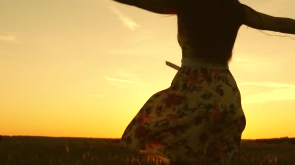 Chica bailando y escuchando música al atardecer en el parque. niña en los auriculares y con un teléfono inteligente giran en vuelo bajo los rayos de la cálida puesta de sol. Movimiento lento . — Vídeos de Stock