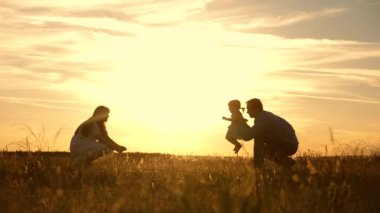 anne ve baba gün batımında parkta çocukla oynarken, çocuk ilk adımları atar. mutlu küçük kızı anne ve baba ile oynarken. mutlu çocuk ebeveynleri ile oynarken.
