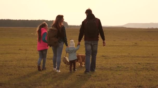 家人带着狗在平原上旅行。一个亲密的家庭的团队合作。母亲,小孩子和女儿和宠物游客。自然运动中的家庭度假的概念. — 图库视频影像
