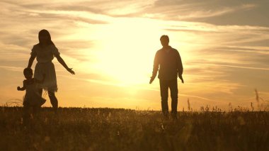 mutlu küçük kızı anne ve baba ile oynuyor. ebeveynlerle oynayan mutlu çocuk. Anne ve baba gün batımında parkta çocuk oynarken, çocuk ilk adımları alır.