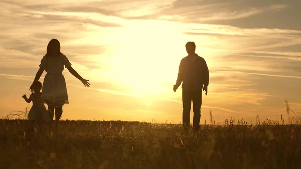 Hija pequeña y feliz jugando con la madre y el padre. niño feliz jugando con los padres. mamá y papá jugando con el niño en el parque al atardecer, niño da los primeros pasos . —  Fotos de Stock