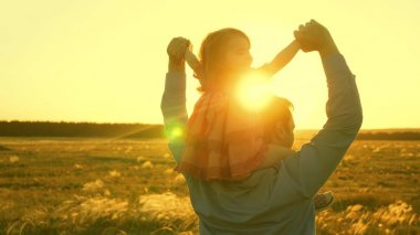 Babamın omuzlarında güneşte kızı ile dans ediyor. Baba gün batımı ışınları içinde omuzlarında bebek ile seyahat ediyor. Ebeveynleri olan bir çocuk gün batımında yürür. mutlu aile parkta istirahat. Aile konsepti