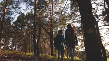 Çam ormanında Hiker Girler. Turist yaşam ve doğa sahiptir. tatil macera seyahat. Mutlu aile seyahatleri. Anne ve kızı yolcuları bir sırt çantası ile ormanda yürüyüş.
