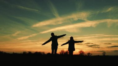 çocuklar uçmayı hayal. takım çalışması gezginler. Çocuklar akşam ları gün batımında oynarlar. kızlar süper kahramanlar güzel gökyüzünün arka planında çayır boyunca çalıştırın. mutlu çocukluk kavramı.