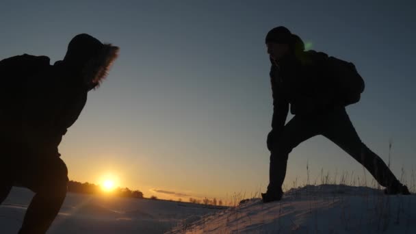 Män hjälper varandra att erövra toppmötet mellan höga snötäckta berg genom att hålla händer och stretching varandra till toppen i solnedgången. Naturliga kyla när du reser. Extrema vandringar för modiga — Stockvideo
