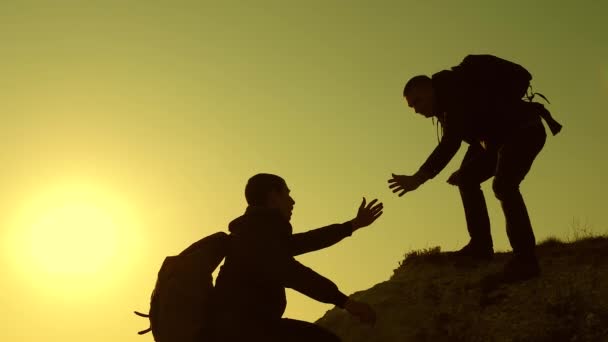 Teamwork of business people. Climbers silhouettes stretch their hands to each other, climbing to top of the hill. travelers climb one after another on the rock. A team of businessmen is going to win. — Stock Video
