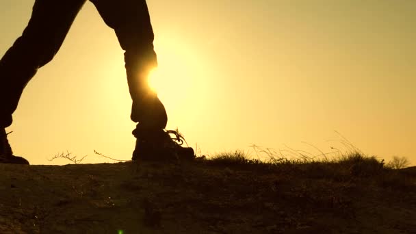 Picioarele unui călător cu un rucsac se plimbă de-a lungul unei creastă pe fundalul soarelui care răsare. Conceptul de călătorie, aventură și turism — Videoclip de stoc