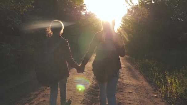 Hiker Girl. šťastné dívky s batohy na zemi jezdí po venkovské silnici, držící ruce v paprscích jasného slunce. koncepce sportovního turismu a cestování. dětské cestovatele. dívky v pubertě cestování a držení — Stock video