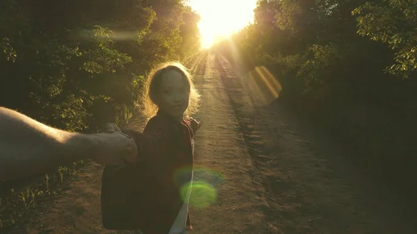 Wandermädchen mit Rucksack hält Mann an der Hand und führt ihn. junges Paar Händchen haltend auf einer Landstraße im Sonnenuntergang. Arbeit in einem Team von Touristen. Verliebte Hände sind unterwegs. Komm mit mir — Stockfoto