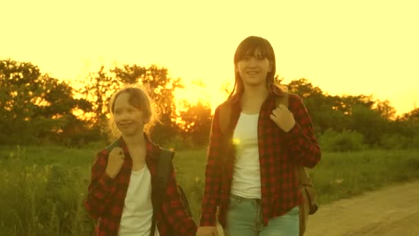 ハイカー・ガール十代の女の子が旅行し、手を握ります。子供の旅行者。バックパックを持つ女の子は、太陽の下で田舎道にいます。スポーツツーリズムと旅行の概念. — ストック動画