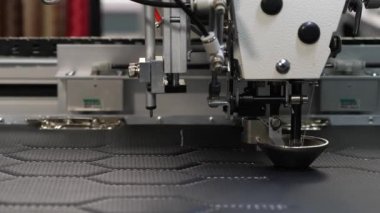 Robotik terzilik üretim hattında çalışır. Robot dikiş makinesi. bilgisayar dikiş makinesini kontrol eder. otomatik dikiş makinesi. suni deri üzerinde iğne nakış deseni.