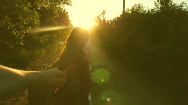Ven conmigo. Hiker Girl con mochila sostiene al hombre a mano y lo lleva. Pareja joven cogida de la mano viajando por carretera en rayos de puesta de sol. trabajar en un equipo de turistas. manos en el amor están viajando . — Vídeos de Stock