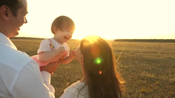 Padre con hijas descansando en el parque. concepto de familia feliz y la infancia. La familia juega con el bebé al atardecer. Papá y mamá caminan con su hija en brazos al atardecer . — Vídeos de Stock