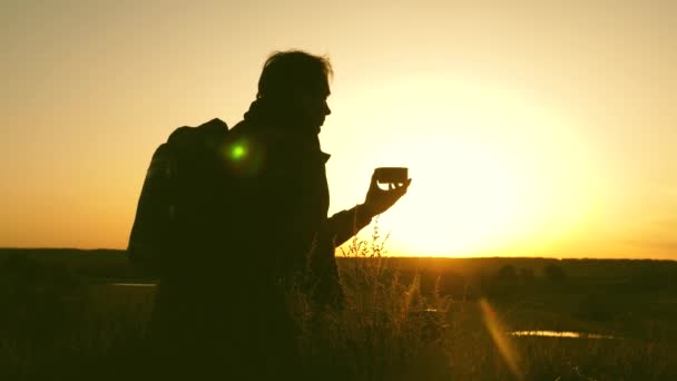 Viaggiatore beve tè caldo e guarda il tramonto. riposo dopo aver raggiunto l'obiettivo. turista solitario seduto in cima alla collina a bere caffè nel thermos. concetto di libertà e sogni. mondo senza frontiere — Video Stock