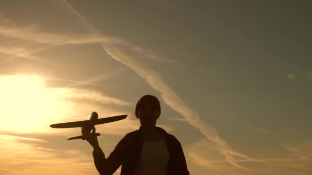 Children on background of sun with an airplane in hand. girl play with a toy plane at sunset. Dreams of flying. Happy childhood concept. Silhouette of children playing on the plane — Stock Video