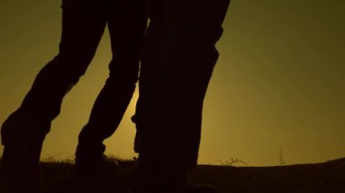 iş adamlarının takım çalışması. üç gezginler birbiri ardına güneş ışınları tepeden inerufuk ötesine gidin. Yavaş çekim. turistler sırt çantaları ile seyahat. iş ekibi kazanmak için acele.