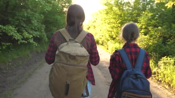 Mom and daughter travel with a backpack against the sky. tourists mother and child go to sunset in the mountains. happy family on vacation travels. sports tourism concept. — Stock Video