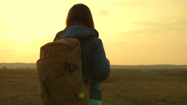Όμορφο κορίτσι ταξιδιώτης με ένα σακίδιο πηγαίνει με τα πόδια το ηλιοβασίλεμα. Τουρίστρια. Η ιδέα στην καμπάνια. Ελευθερία και ανεξαρτησία. Πεζοπορία. — Αρχείο Βίντεο