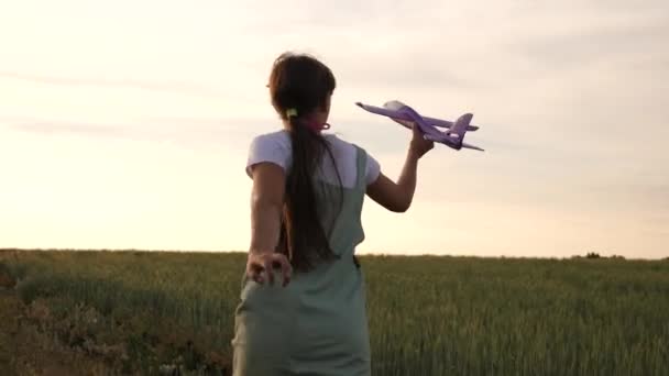 Joyeux fille court avec un avion jouet sur un champ de blé. enfants jouent jouet avion. adolescent rêve de voler et de devenir pilote. la fille veut devenir pilote et astronaute .