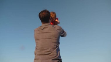 Babam kızını mavi gökyüzüne fırlatıyor. Babam küçük bir çocukla oynuyor. mutlu aile gökyüzüne karşı akşam oynarken. Babam bebeği kusuyor, çocuk gülümsüyor. Yavaş çekim. baba ve küçük kızı