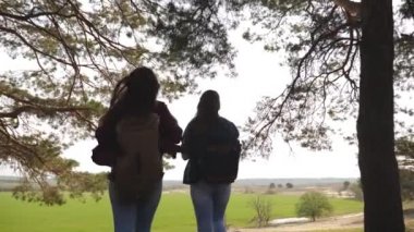 Kadınlar turistler ormana gider. Sırt çantalarına sahip seksi kadın yolcular, özgürlüğün tadını çıkarırken kollarında kollarını düzleştirecek. Kız el tutun ve gülmek. Kampanyada maceralar. Takım çalışması.