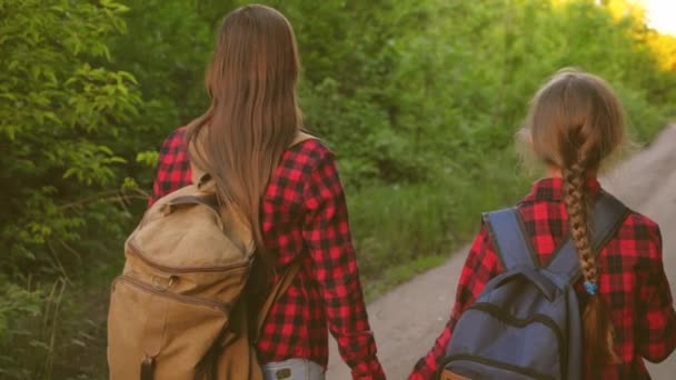 Máma s dcerou cestují s batohu proti nebi. Turisté a matka a dítě jdou do hor na západ slunce. šťastná rodina na dovolené. koncepce sportovního turismu. — Stock video