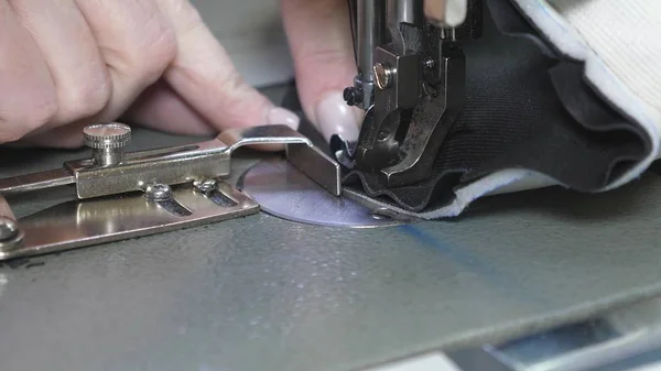 Die Nadel der Nähmaschine bewegt sich schnell auf und ab. Prozess des Nähens von Lederwaren. Schneider näht schwarzes Leder in Nähwerkstatt. Nadel der Nähmaschine in Bewegung, Nahaufnahme. — Stockfoto