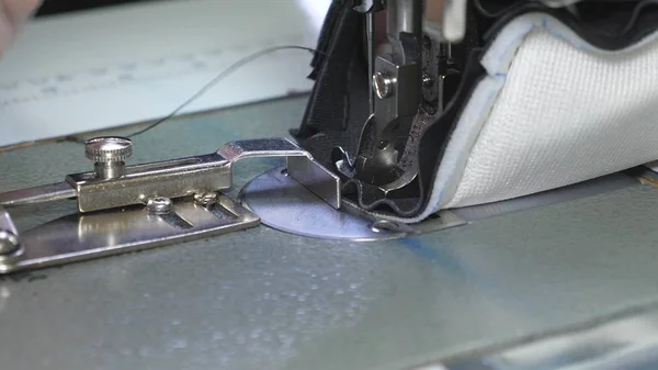 Die Nadel der Nähmaschine bewegt sich schnell auf und ab. Prozess des Nähens von Lederwaren. Schneider näht schwarzes Leder in Nähwerkstatt. Nadel der Nähmaschine in Bewegung, Nahaufnahme. — Stockfoto