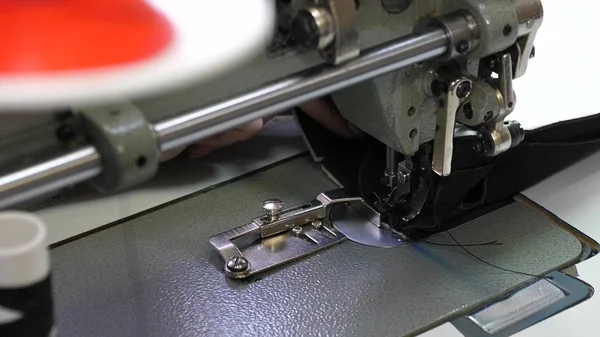 Die Nadel der Nähmaschine bewegt sich schnell auf und ab. Prozess des Nähens von Lederwaren. Schneider näht schwarzes Leder in Nähwerkstatt. Nadel der Nähmaschine in Bewegung, Nahaufnahme. — Stockfoto