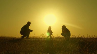 Anne ve baba küçük kızları ile oynarlar. mutlu çocuk babadan anneye geçer. anne ve baba güneşte kızları ile oynamak. 1 yıllık bir çocuk ile genç aile. aile mutluluğu kavramı.