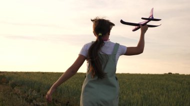 Mutlu kız bir buğday tarlası üzerinde bir oyuncak uçağı ile çalışır. çocuklar oyuncak uçak oynamak. uçan ve bir pilot olma genç rüyalar. kız bir pilot ve astronot olmak istiyor.