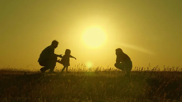 Mom and dad play with their little daughter. happy child goes from father to mother. mother and Dad play with their daughter in sun. young family with a child of 1 year. family happiness concept. — Stock Photo, Image