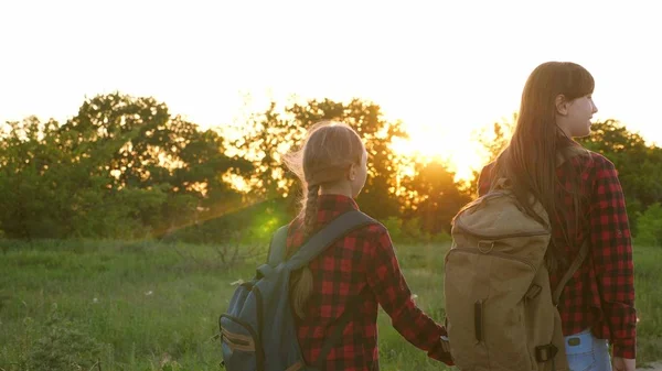 Turistické dívky na venkovské silnici. Hiker Girl, dívky cestují a drží se za ruce. dětské cestovatele. dívky s batohy jsou na venkovské silnici na slunci. koncepce sportovního turismu a cestování — Stock fotografie