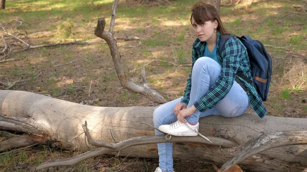 Mujer viajera paseando por el bosque con una mochila y un perro. Hiker Girl atando cordones en zapatillas. en un viaje. El turista disfruta de la vida y la naturaleza. vacaciones, mascotas —  Fotos de Stock