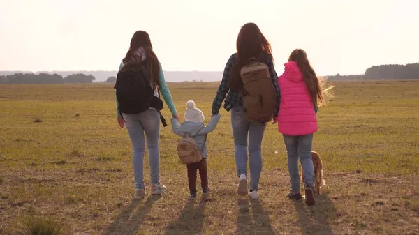 Familie met rugzakken reist met een hond. teamwork van een hechte familie. moeder, dochters en huisdieren toeristen. concept van een sportieve familie vakantie in de natuur. — Stockfoto