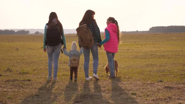 Familj med ryggsäckar reser med en hund. Teamwork av en nära sammansvetsad familj. mor, döttrar och hem husdjur turister. begreppet en sport familjesemester i naturen. — Stockfoto