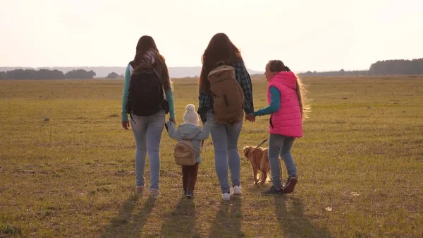 Familie met rugzakken reist met een hond. teamwork van een hechte familie. moeder, dochters en huisdieren toeristen. concept van een sportieve familie vakantie in de natuur. — Stockfoto