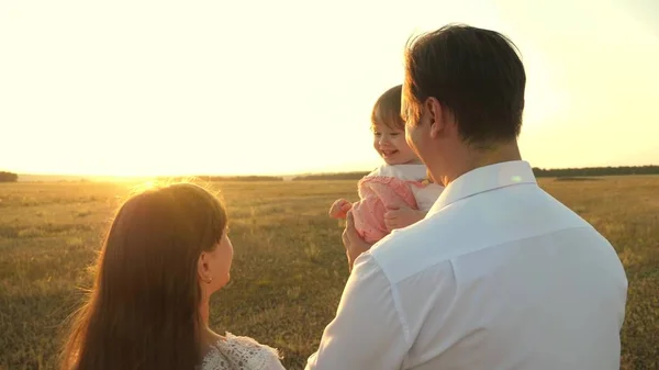 아빠와 엄마는 일몰에 그녀의 팔에 작은 딸과 놀고. 가족은 일몰에 아이와 함께 산책. 공원에서 쉬고 있는 딸들과 놀고 있는 아버지. 행복한 가족과 어린 시절의 개념. — 스톡 사진