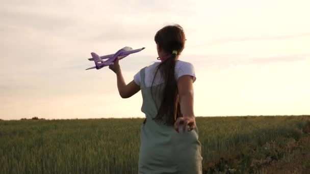 Joyeux fille court avec un avion jouet sur un champ de blé. enfants jouent jouet avion. adolescent rêve de voler et de devenir pilote. la fille veut devenir pilote et astronaute .