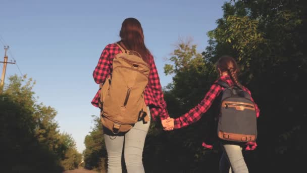 Genç kızlar seyahat ve eller tutun. Hiker kız. Çocuk yolcuları. sırt çantaları olan kızlar güneşin içinde ülke yolunda. Spor turizmi ve seyahat konsepti. — Stok video