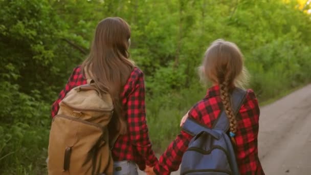Mom and daughter travel with a backpack against the sky. tourists mother and child go to sunset in the mountains. happy family on vacation travels. sports tourism concept. — Stock Video